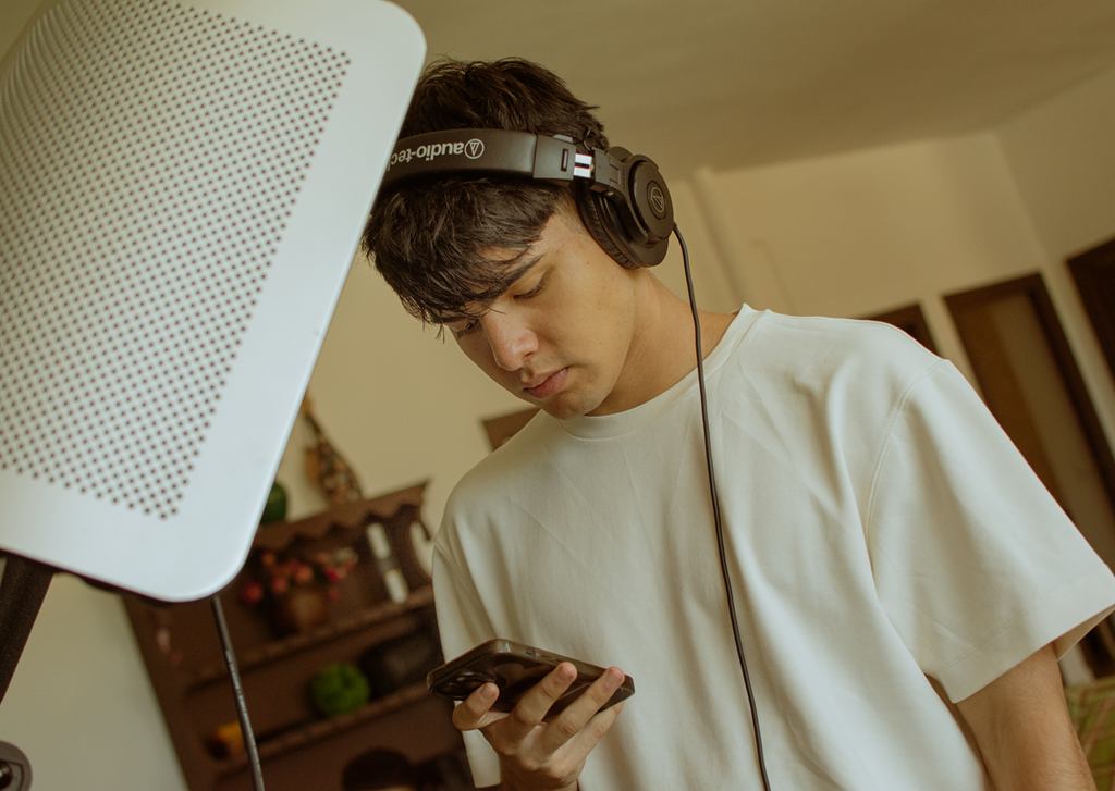 Productor con auriculares revisando una maqueta en el móvil